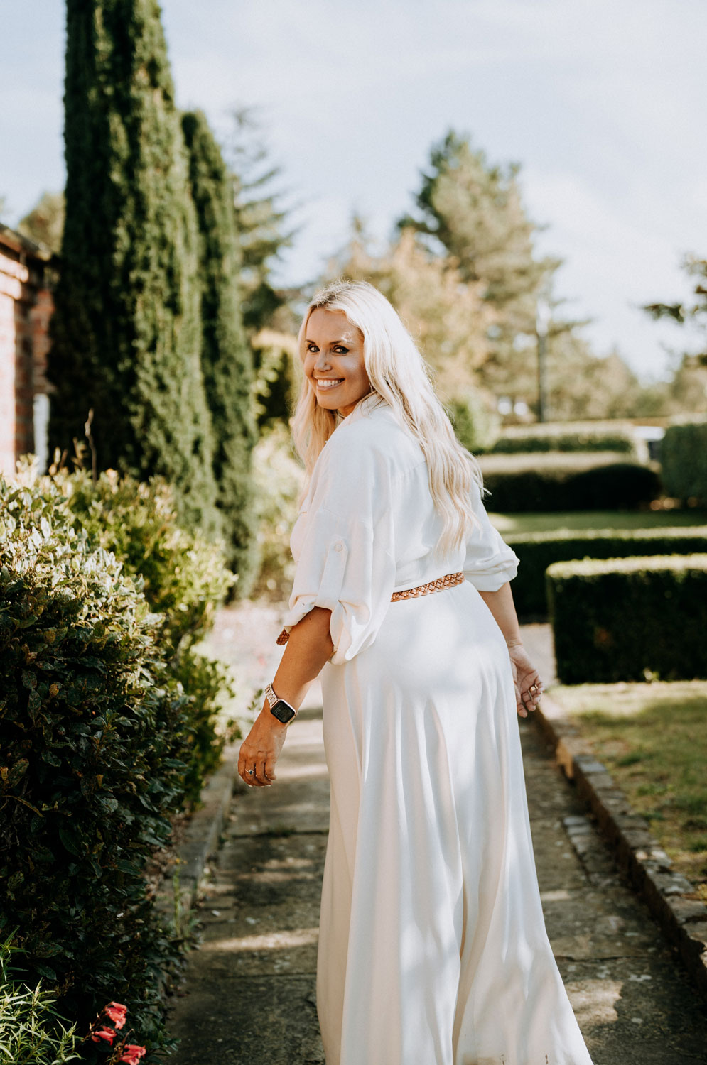 Caroline in a garden looking over her shoulder